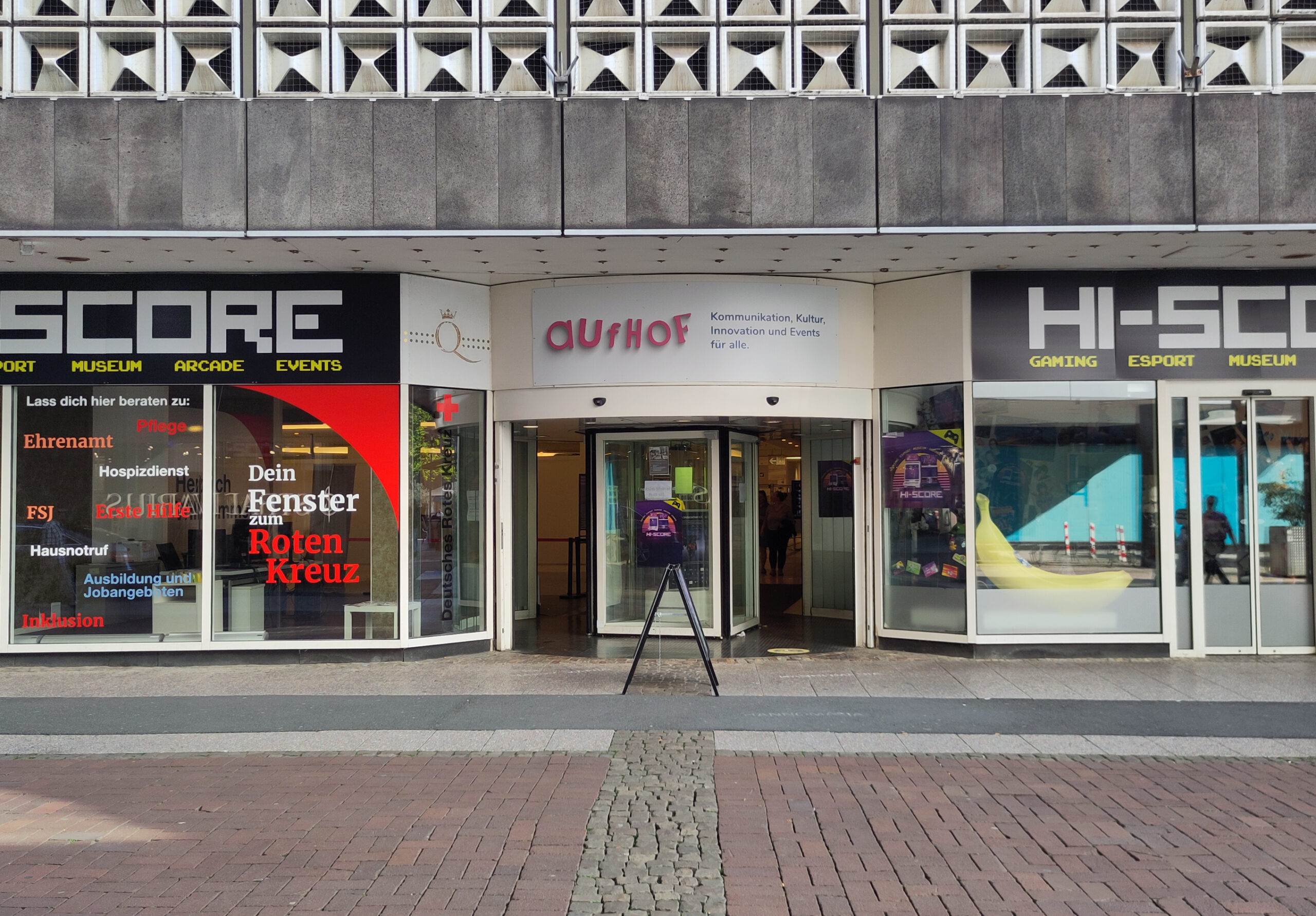 The picture shows an entrance to a building. On top a sign says "aufhof. Kommunikation, Kultur, Innovation und Events für alle."