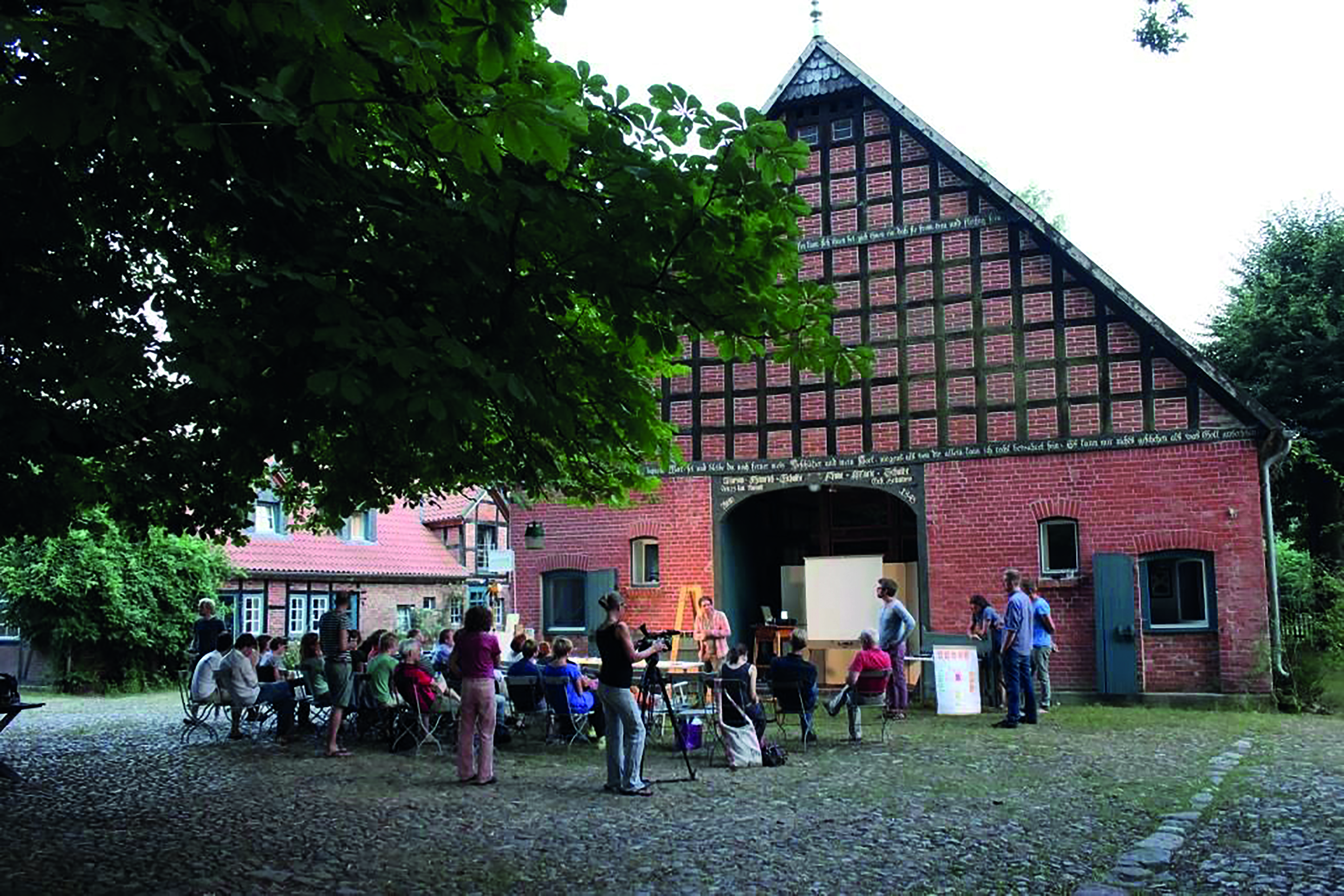Das Bild zeigt eine Gruppe Personen vor einem Fachwerkhaus - die Grüne Werkstatt Wendland.