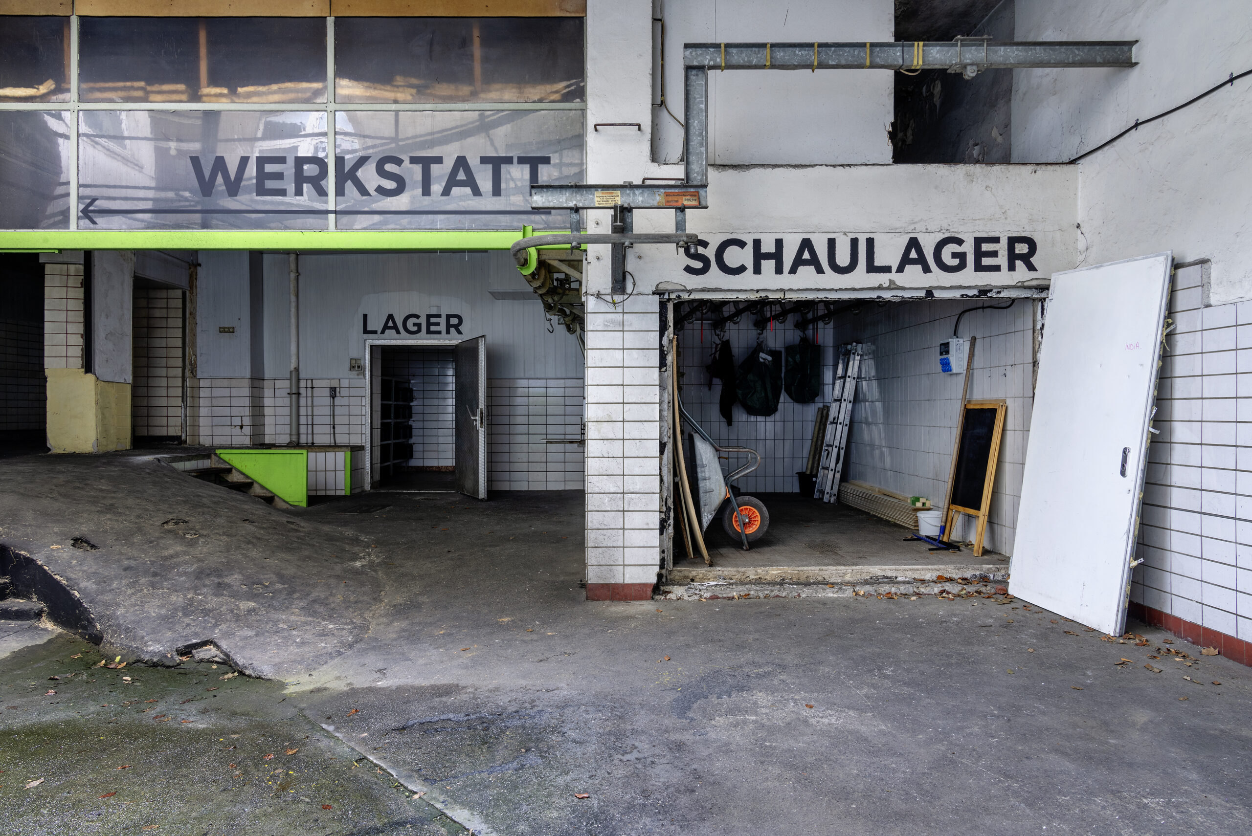 Das Foto zeigt einen Blick in das Schaudepot des UmBauLabors. Drei Schriftzüge unterteilen die Räume in "Werkstatt", "Lager" und "Schaulager".